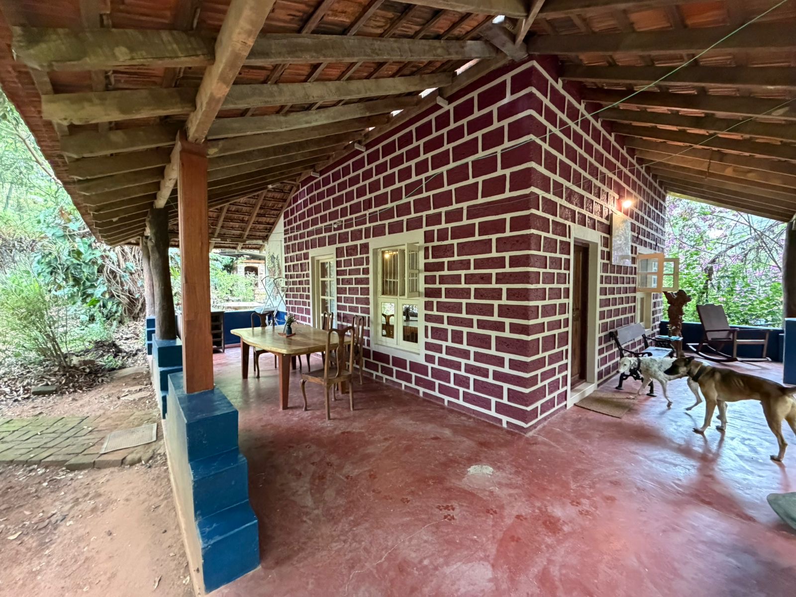 Covered brick veranda with dining table and resident dogs