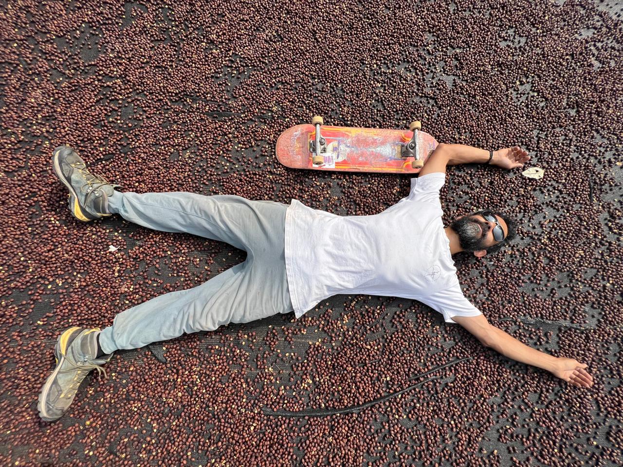 Soms lying on a bed of drying coffee cherries next to his skateboard